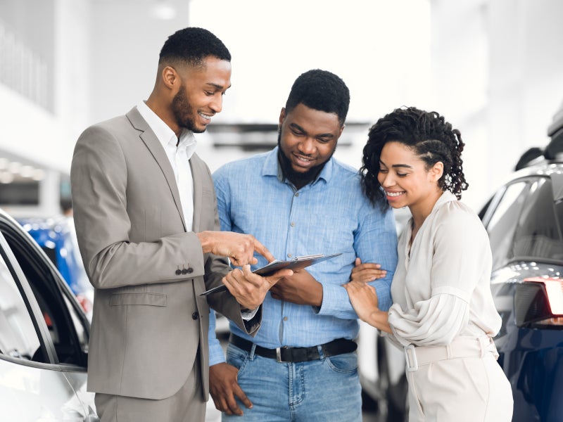 car salesman talking to couple in showroom